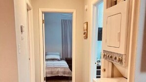 A narrow hallway with a bed at the end, a washing machine, and a radiator on the left. - welcome to the soonerschooner (Norman)