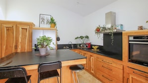 A kitchen with wooden cabinets, a black countertop, a sink, a stove, and various potted plants. - Stunning home in Darbres (Darbres)