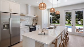 A modern kitchen with a central island, stainless steel appliances, and pendant lighting. - 3BR Lux Home, Heated Pool, Fire Pit, Outdoor TV (Palmetto)