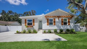 A single-story house with a front porch, a small garden, and a white exterior. - 3BR Lux Home, Heated Pool, Fire Pit, Outdoor TV (Palmetto)