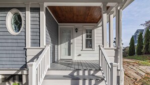 A porch with white railings, a wooden ceiling, and a door with glass panels. - Kennebunk's Golf and Beach Haven (Kennebunk)