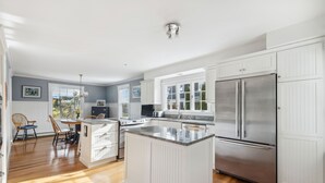 A modern kitchen with white cabinetry, a stainless steel refrigerator, and a wooden island. - Kennebunk's Golf and Beach Haven (Kennebunk)