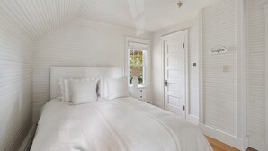 A bedroom with a large bed, a window with a view of trees, and a door with a sign that says "imagine". - Kennebunk's Golf and Beach Haven (Kennebunk)