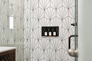 A bathroom with a geometric patterned wall, a sink, and a shelf with toiletries. - 3 king suites + private heated pool, just steps to resort amenities. (Kissimmee)