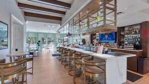 Un espace bar moderne avec des tabourets hauts, un long comptoir et un écran de télévision.