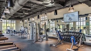 Une salle de sport équipée de divers appareils d’exercice, notamment des tapis de course, des appareils de musculation et des haltères.