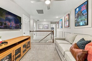 A hallway with a wooden bench, a couch, and a staircase with a white railing. - 3 king suites + private heated pool, just steps to resort amenities. (Kissimmee)
