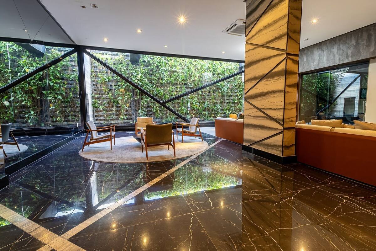 A modern lobby with a glass wall, a circular seating area, and a red sofa.