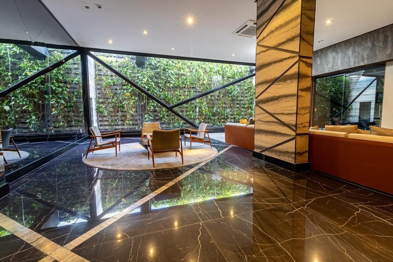 Un lobby moderno con un muro de vidrio, un área de estar circular y un sofá rojo.