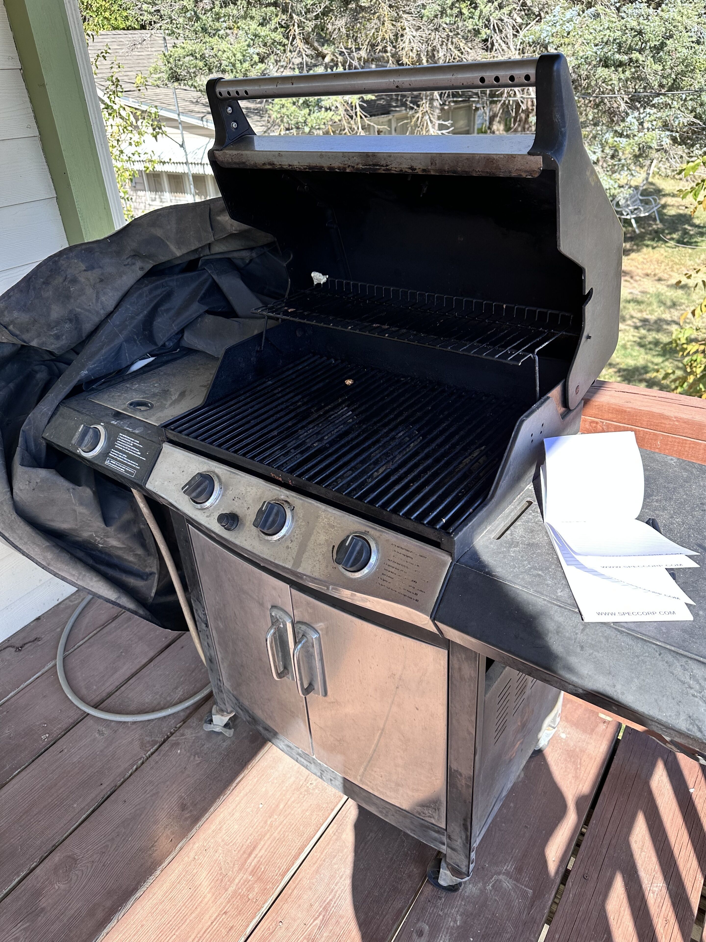 En grill med kontrollpanel, en gasledning och en meny som sitter fast på sidan.
