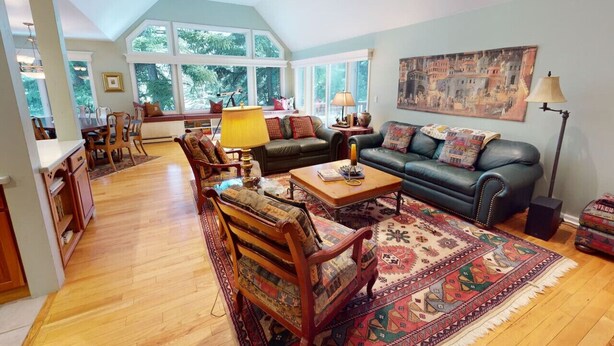 A spacious living room with a high ceiling, large windows, a cozy seating area with a sofa and chairs, a coffee table, and a patterned rug. - Large Family Home - Beaver Creek (Avon)