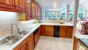 A modern kitchen with wooden cabinets, a dishwasher, and a large window offering a view of the outdoors. - Large Family Home - Beaver Creek (Avon)