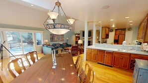 A spacious dining area with a wooden table and chairs, a chandelier, and a view of the outdoors. - Large Family Home - Beaver Creek (Avon)