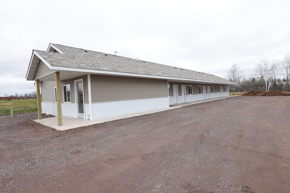A long, single-story building with a covered porch and multiple doorways, likely a stable or barn.