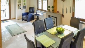 A dining area with a glass table, black chairs, and a green placemat. There is a small plant on the table and a window with a view of trees. - 3 bedroom beautiful home in Kirchheim (Kirchheim)