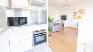 Une cuisine moderne équipée d’un four à micro-ondes, d’un four traditionnel et d’une plaque de cuisson intégrée. On y trouve un coin repas avec une table et des chaises, ainsi qu’un petit coin salon avec un canapé.