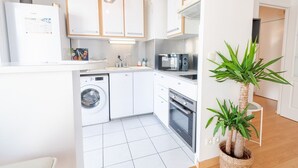 Une cuisine compacte équipée d’un lave-linge, d’un four, d’un four à micro-ondes et d’un évier.