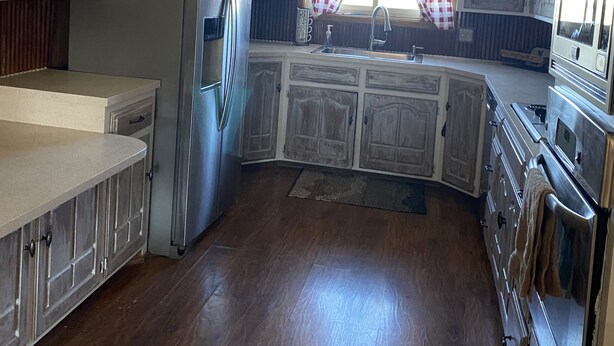 A kitchen with wooden cabinets, a stainless steel refrigerator, and a built-in oven. - Peaceful country farmhouse. Located 5 minutes from Historic downtown Post! (Post)