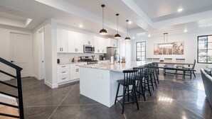 A modern kitchen with white cabinets, a large island, and bar stools.