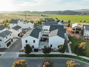 A residential area with modern houses, a swimming pool, and a green field in the background. - Two homes in one! Beautiful Courtyard with Pool! (Hurricane)