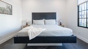 A modern bedroom with a large bed, bedside tables, and a window.
