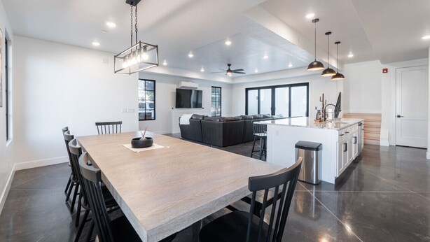 A spacious kitchen with a central island, a dining area with a long table, and a modern ceiling fan. - Two homes in one! Beautiful Courtyard with Pool! (Hurricane)