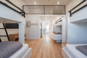 Una habitación de hotel moderna y compacta con literas, suelo de madera y escalera que lleva a un nivel superior.