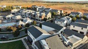 A residential area with multiple houses, a swimming pool, and a clear view of the surrounding landscape.