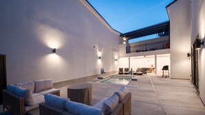 A modern outdoor patio with a pool, wicker furniture, and a balcony with a dining area. - Two homes in one! Beautiful Courtyard with Pool! (Hurricane)