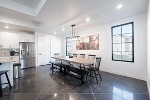 A modern kitchen with a dining area, stainless steel appliances, and a large window.