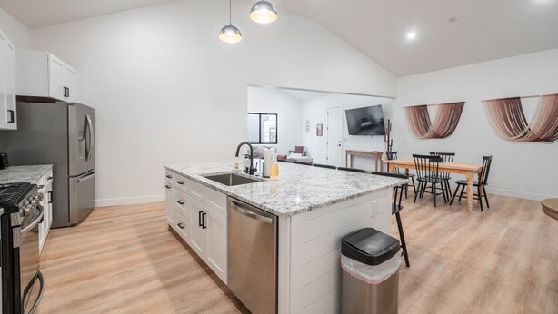 A modern kitchen with a central island, stainless steel appliances, and pendant lighting.