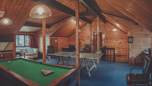 Ein gemütlicher Freizeitraum mit Holzboden, Billardtisch, Tischtennisplatte und Poolbillard.