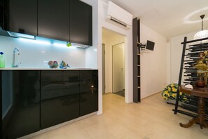 A modern kitchen with black cabinets, a built-in oven, and a countertop with a water dispenser. - Charming 38 sqm studio apartment, able to accommodate up to 3 people, located on the ground floor of a building overlooking a quiet pedestrian alley (1 step to access it). The accommodation is located in the heart of the island of Ortigia, the historic c (Siracusa)