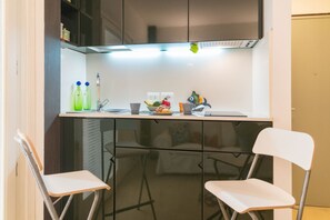 A compact kitchen with a white countertop, two chairs, and a small dining area. - Charming 38 sqm studio apartment, able to accommodate up to 3 people, located on the ground floor of a building overlooking a quiet pedestrian alley (1 step to access it). The accommodation is located in the heart of the island of Ortigia, the historic c (Siracusa)