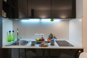 A modern kitchen with a stainless steel sink, a bowl of fruit, a croissant, and a fish decoration.