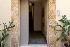 A narrow entrance with a door, a staircase, and potted plants.