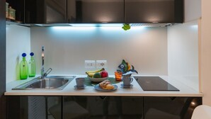 Une cuisine moderne avec un évier en acier inoxydable, un panier de fruits, un croissant et une décoration en forme de poisson.