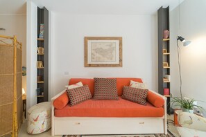 A room with a sofa, a map on the wall, and shelves with books and decorative items.