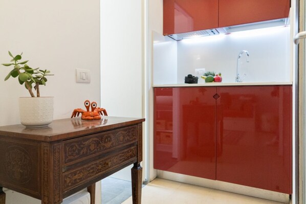 A kitchen with red cabinets, a white countertop, a plant, and a decorative crab.