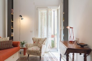 A living room with a sofa, a chair, a table, and a lamp.