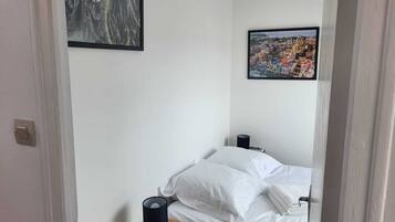 Una camera da letto con un letto, un comodino con una lampada e due quadri appesi al muro.