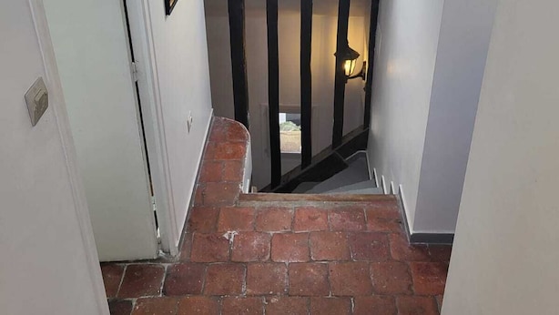 A staircase with a skylight, brick steps, and a framed picture on the wall.