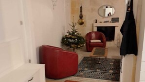 A cozy living room with a red sofa, a small Christmas tree, and a fireplace.