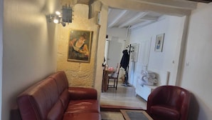 A living room with a leather sofa, a matching armchair, a patterned rug, and a painting on the wall.