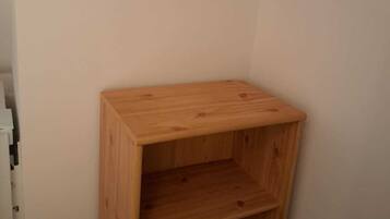 A corner room with a wooden shelf unit against the wall.