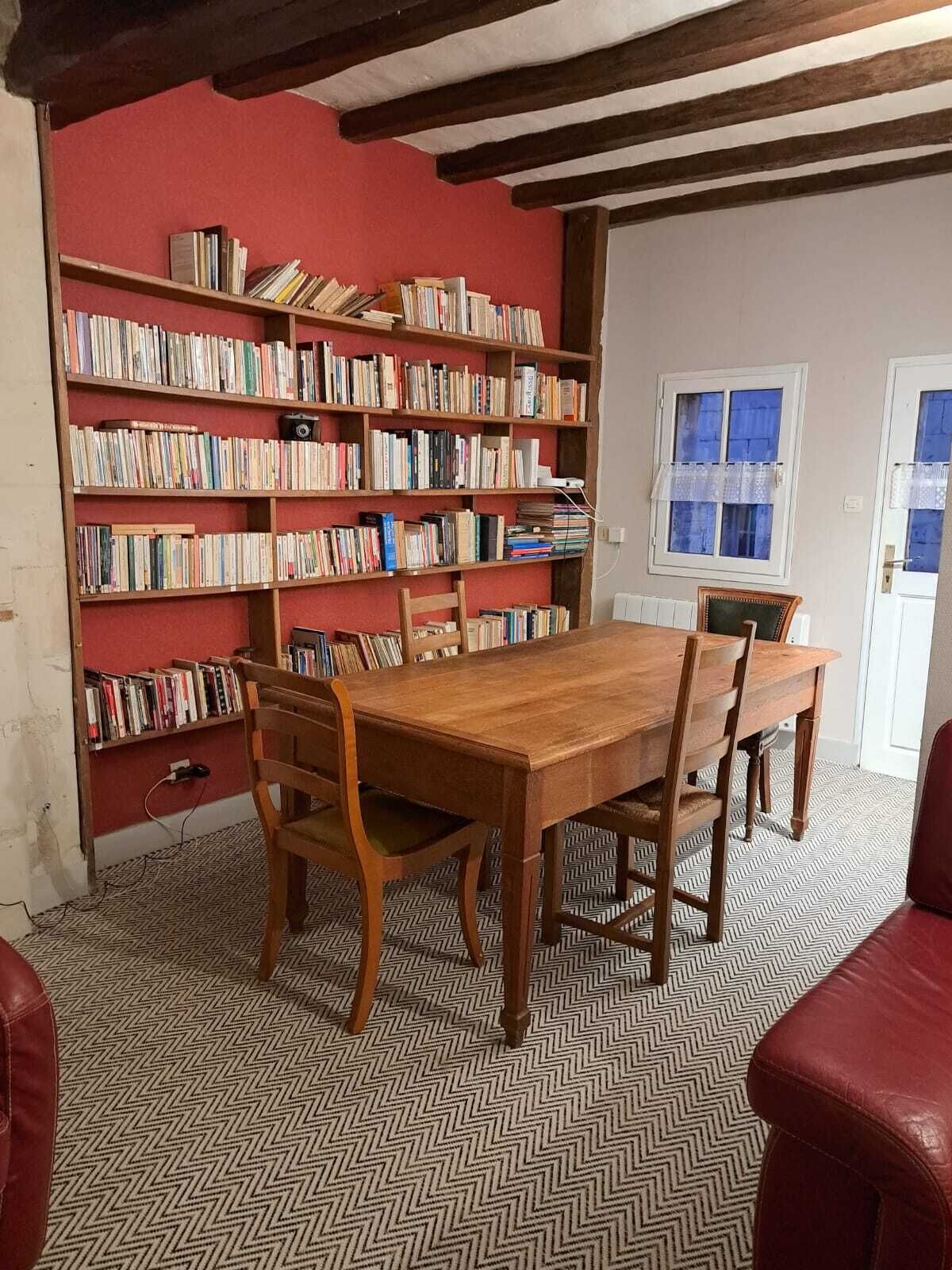 A dining area with a wooden table and chairs, surrounded by bookshelves filled with books.
