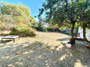 A backyard with a fire pit, a tree, and a hanging bird feeder. - Monthly Furnished 2-Bedroom Steps From Ocean (Victoria)
