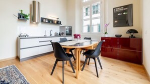 Et moderne køkken med spiseplads, med et stort vindue, et rødt skab og en sort stol.