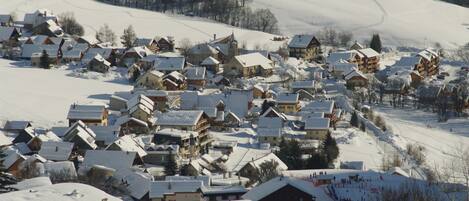 Un pueblo cubierto de nieve con casas de madera tradicionales y una pista de esquí.