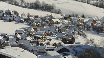 Un village enneigé, avec ses maisons traditionnelles en bois et une piste de ski.